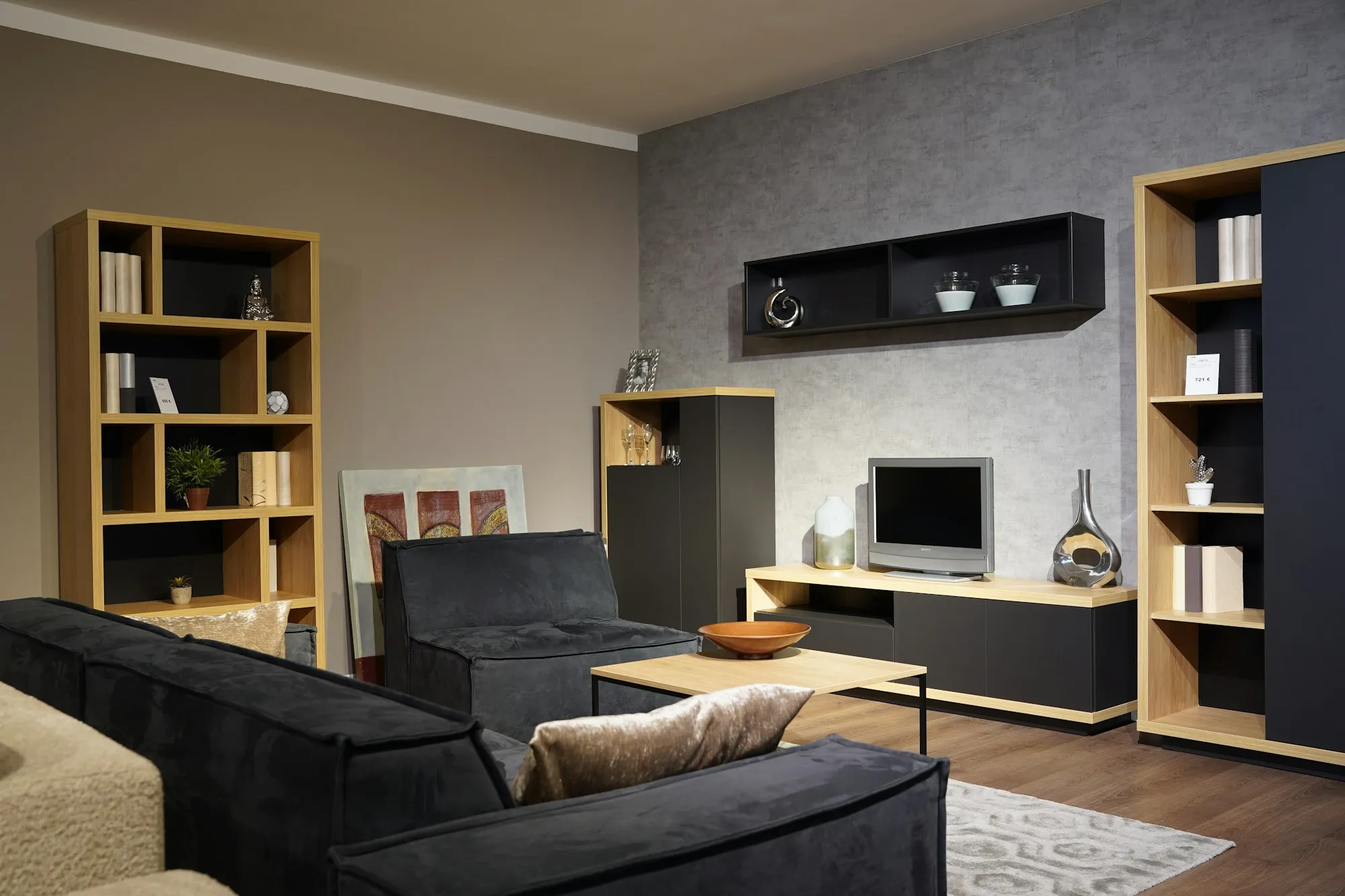 Wohnraum mit eingebauten Regalen und Sideboard aus hellem Holz über die volle Wandhöhe